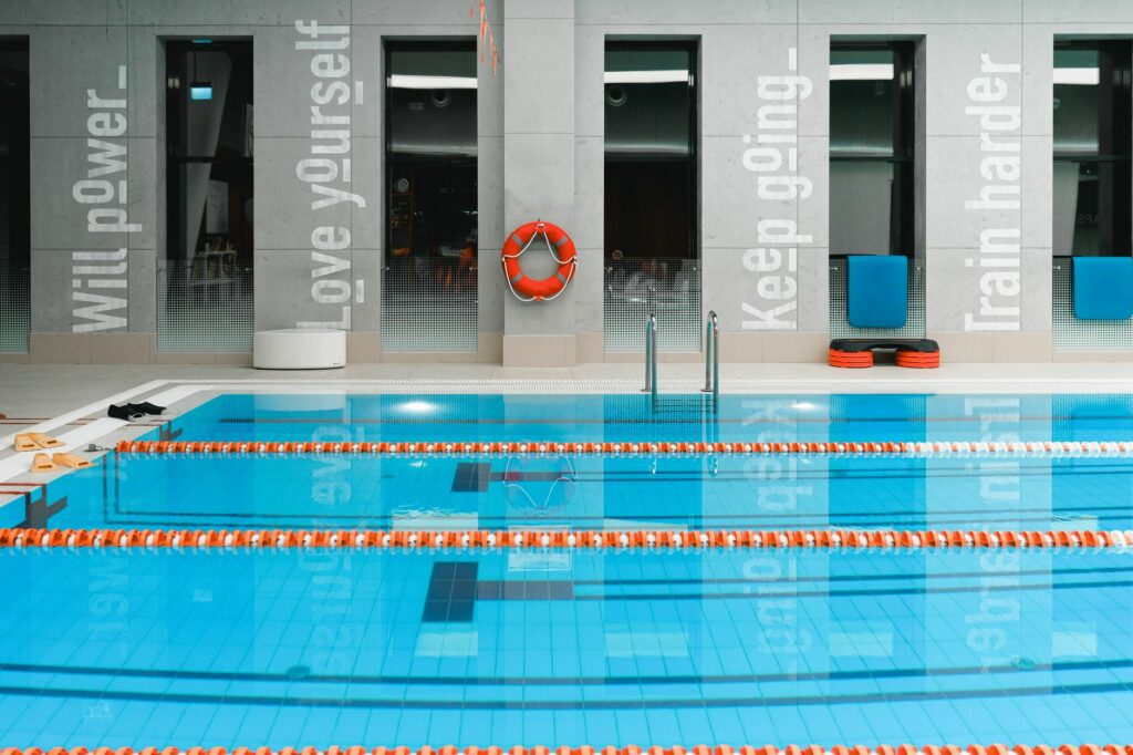 A modern indoor swimming pool with motivational quotes on the walls and clear water.